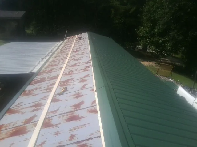 Old rusted panels beside newly installed green metal roofing — Wind Damage Roof Repair by Roofing Brothers in Notus