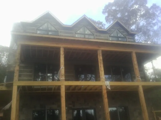 Dormers and porch framing on a large log home under construction — Roof Coating work by our crew in Notus