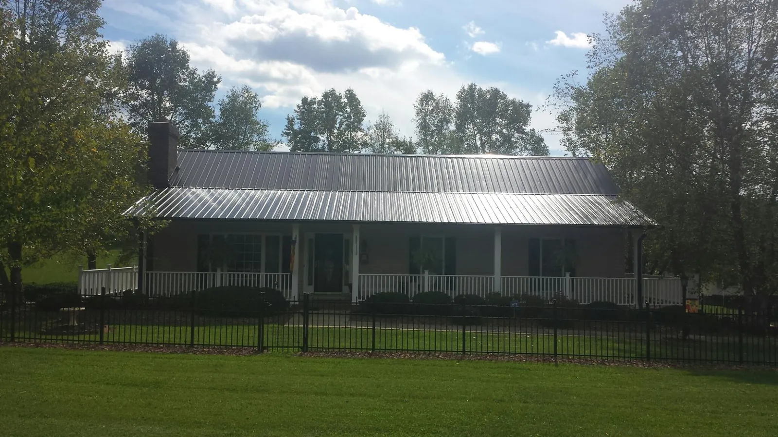 Gray metal roof on a brick ranch with a full width front porch — Gutter Guard Installation work by our crew in Notus