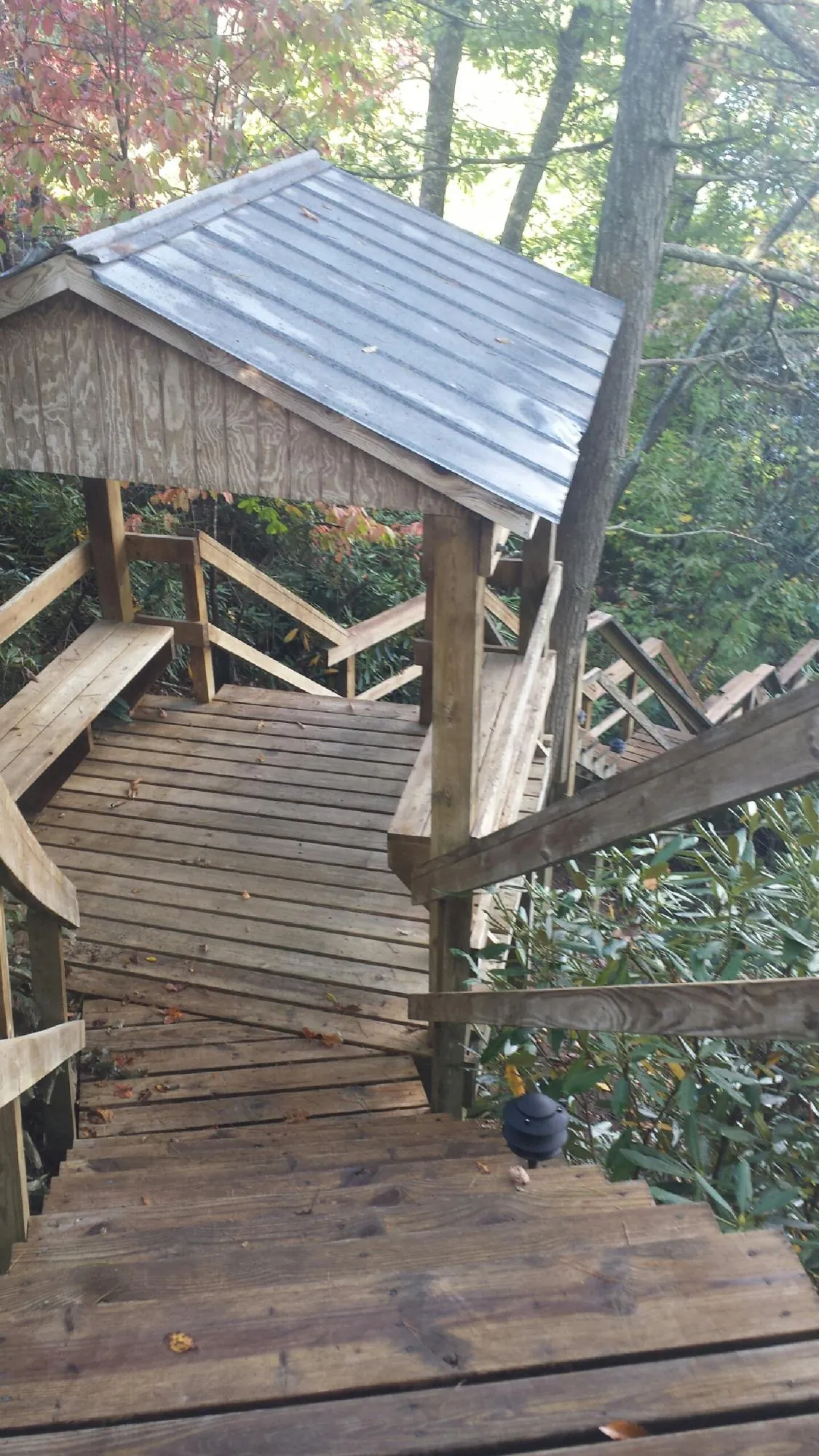 Metal roofed shelter over wooden steps on a wooded walkway — Skylight Repair & Installation work by our crew in Notus