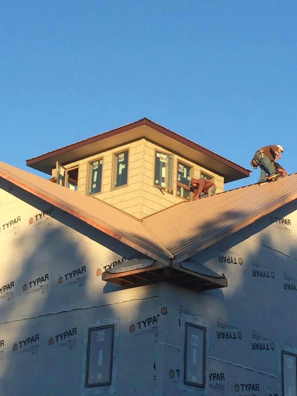 Roofers working around a rooftop cupola on a new metal roof at sunset — Roof Waterproofing in Notus by Roofing Brothers